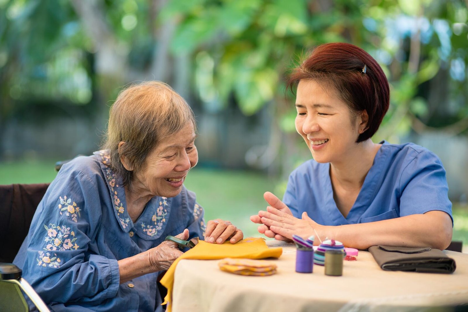 Elderly woman with caregiver in the needle crafts occupational therapy for Alzheimer’s or dementia