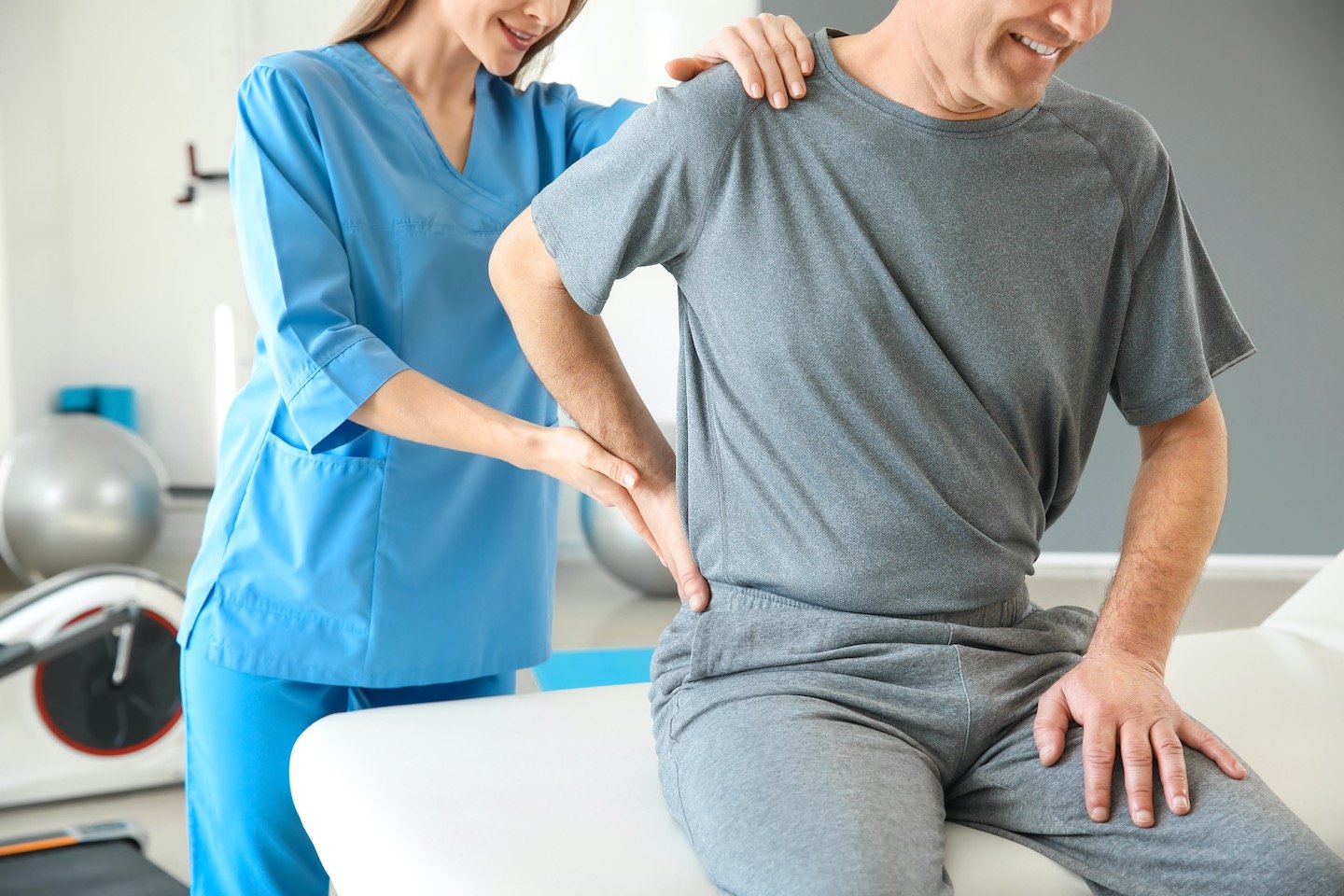 Physiotherapist working with mature patient in rehabilitation center treating a person with back pain